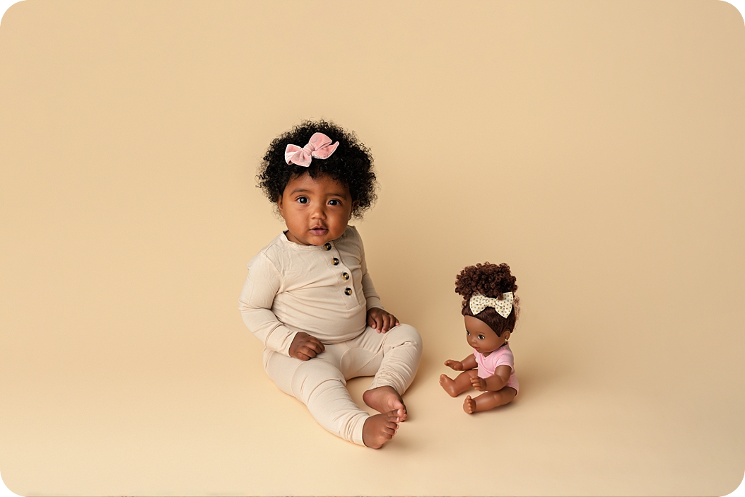 baby plays with doll during classic 8 month milestone portraits