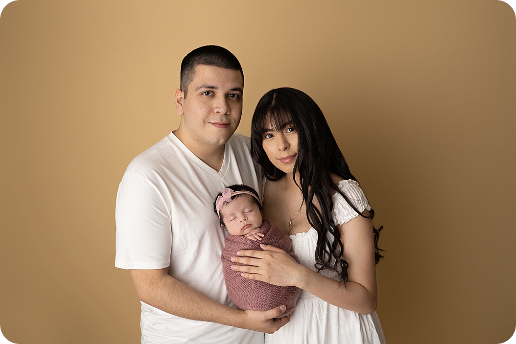 new parents hold baby girl during studio newborn portraits in Utah