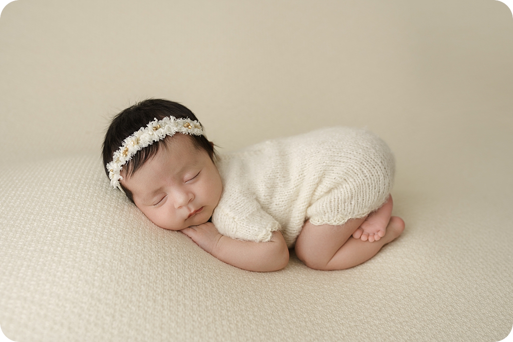 baby girl in white outfit sleeps during studio newborn portraits in Utah