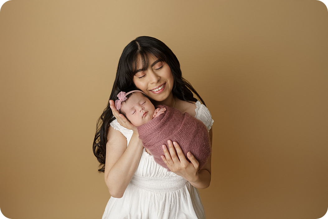 mom snuggles with daughter during studio newborn portraits in Utah