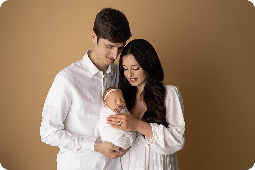 mom and dad look at baby girl during Studio Newborn Session in Utah 