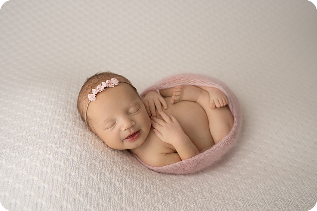 baby girl smile in pink wrap during Studio Newborn Session in Utah 