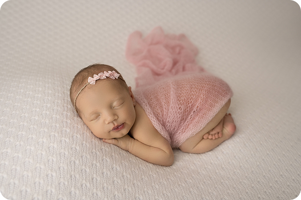 baby lays in pink wrap during UT newborn photos 