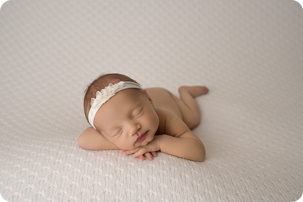 newborn portraits of baby girl laying on white blanket