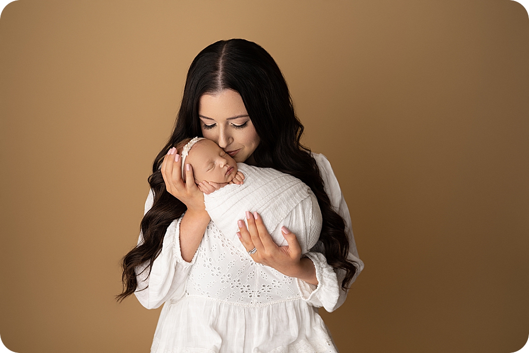 mom kisses baby girl during newborn photos in Utah