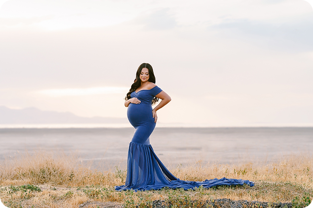 mother looks down at belly in blue gown
