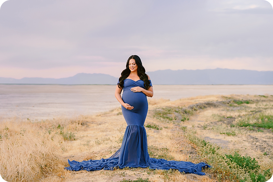 mom-to-be holds belly in blue dress