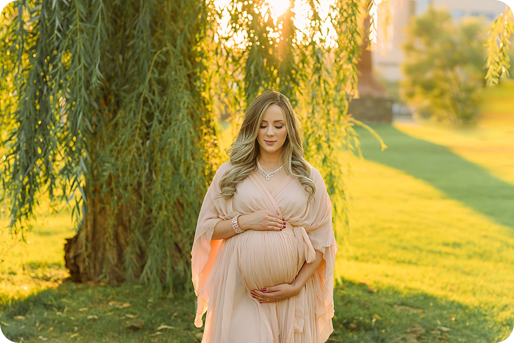 mom poses in weeping willow during maternity photos