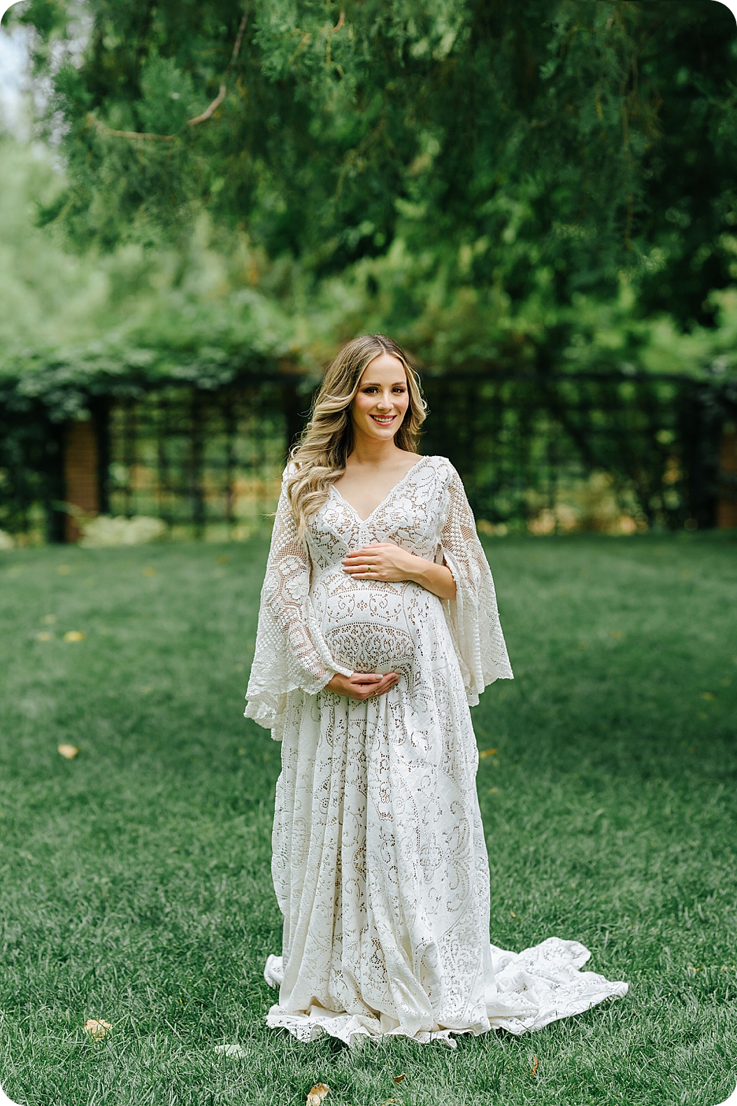 mom poses in boho gown during garden maternity session