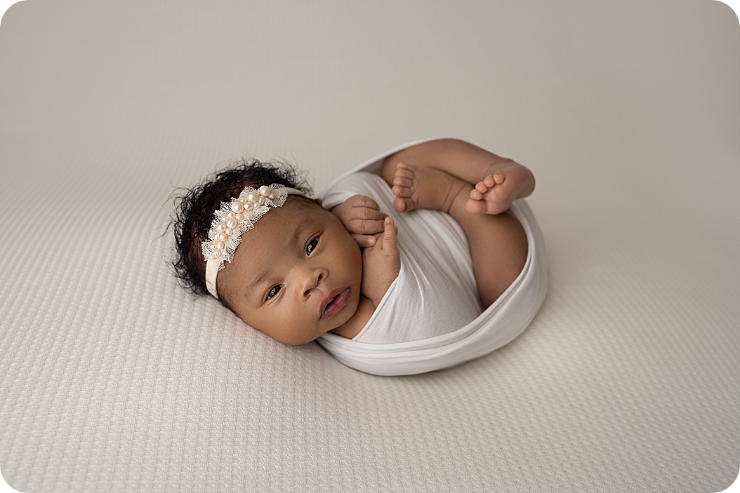 baby lays in white wrap during Utah newborn portraits 
