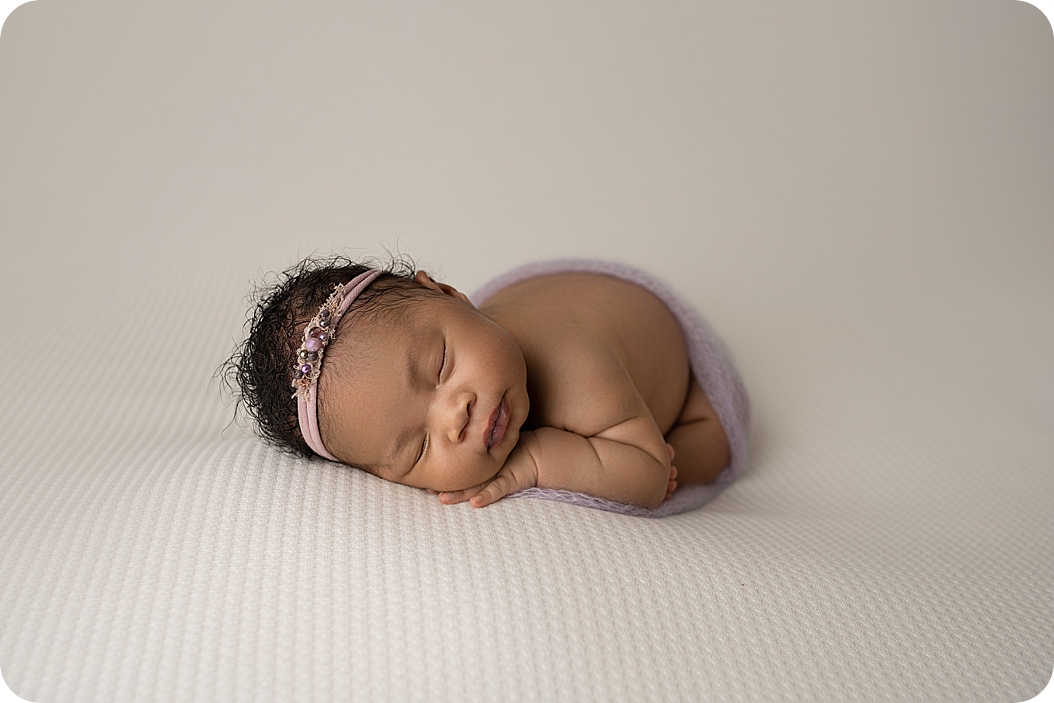 baby sleeps with purple headband during stylish newborn portraits