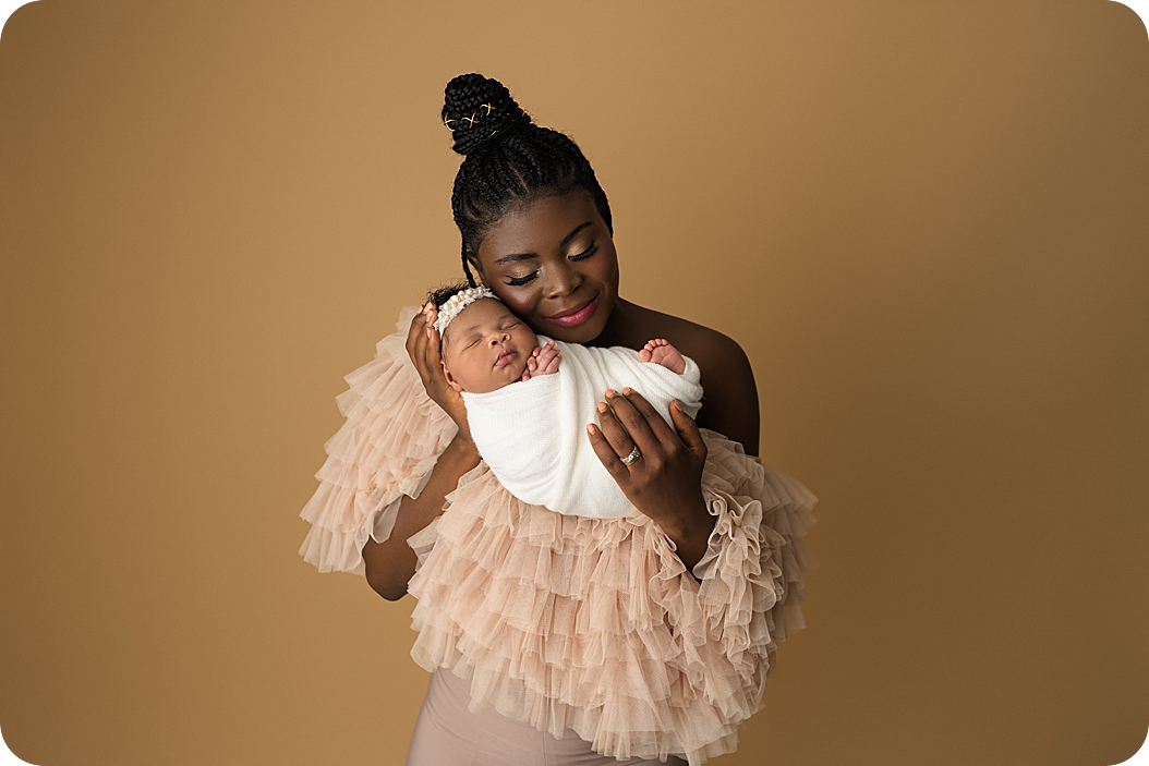 mom holds baby girl during stylish newborn portraits in Utah studio