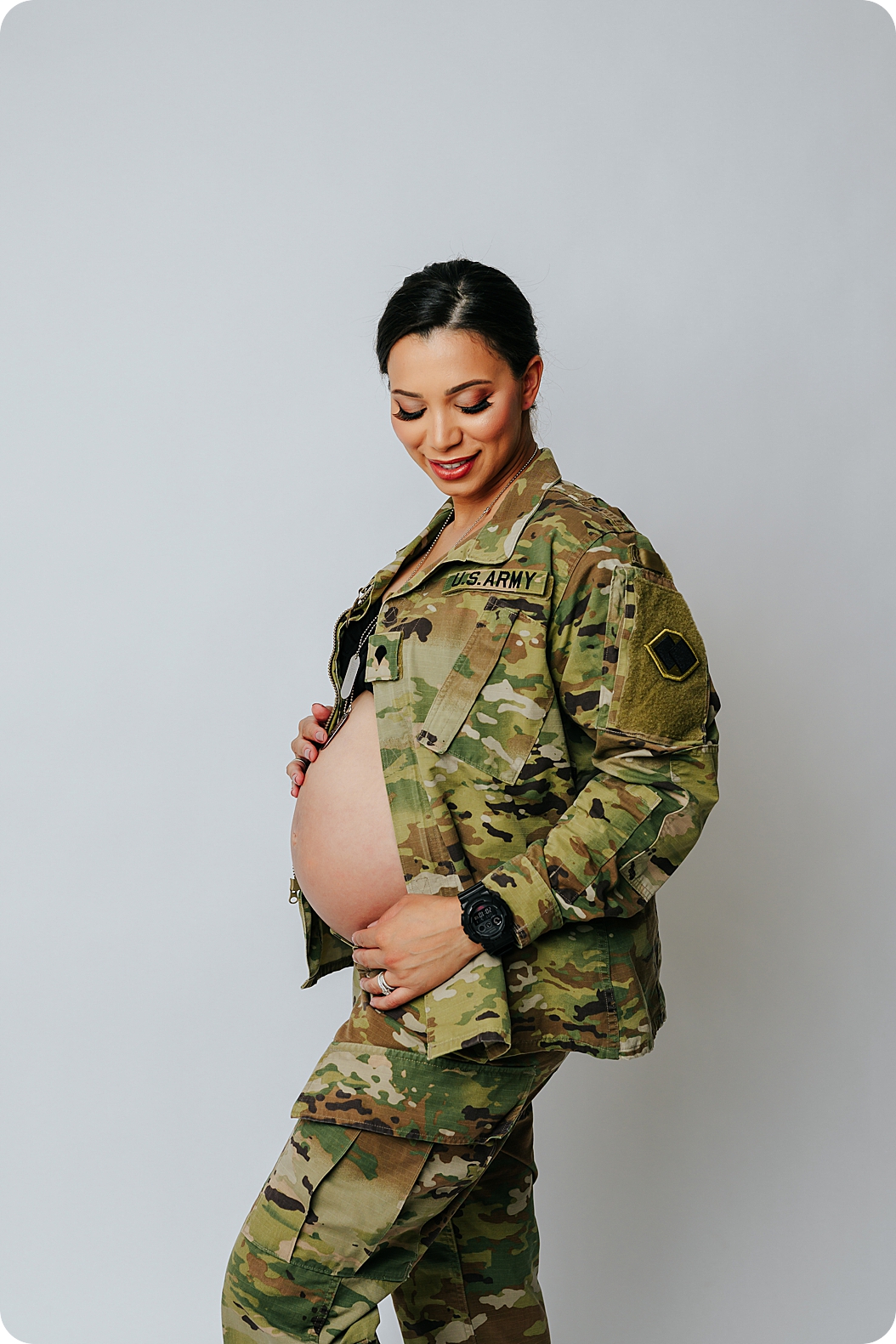 expecting mom in Army jacket holds belly