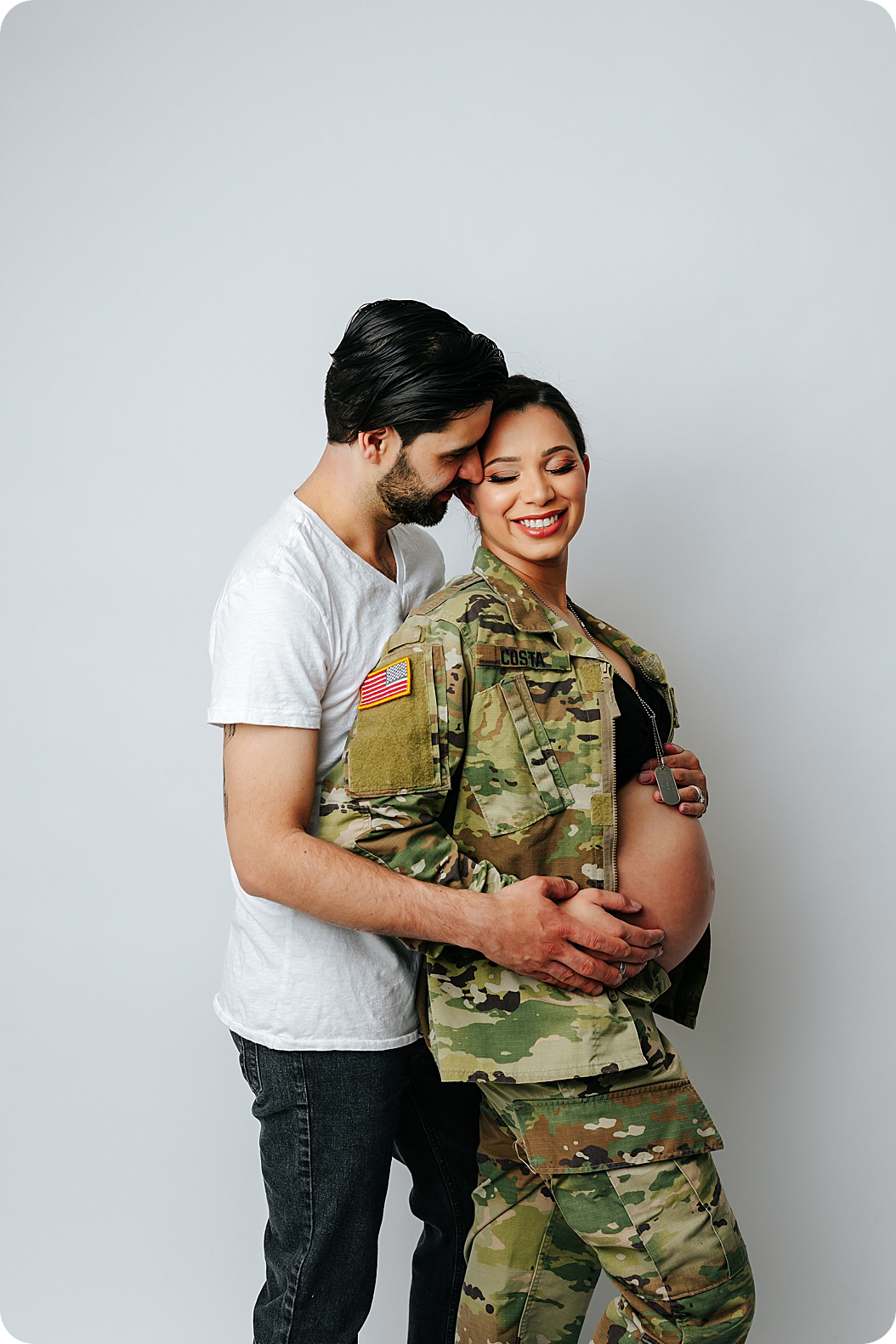 husband hugs wife in army jacket