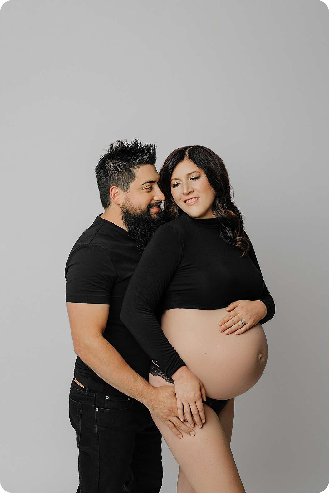 expecting parents pose together during studio maternity session