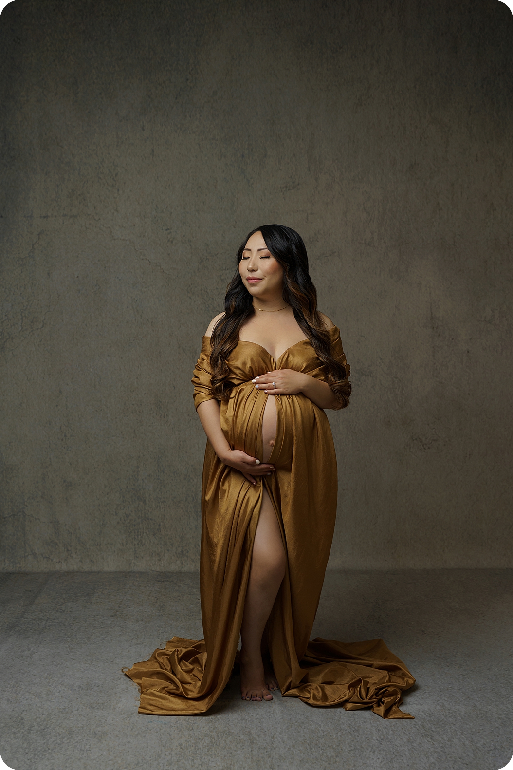 woman poses in studio with gold fabric over belly