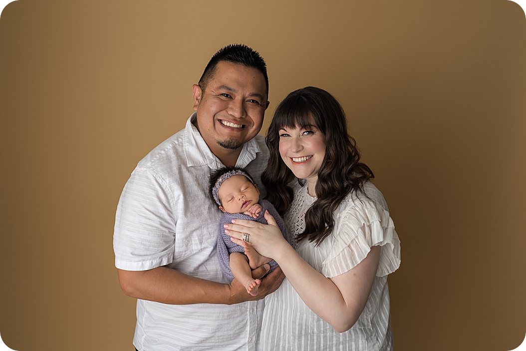 family of three snuggles during newborn photos