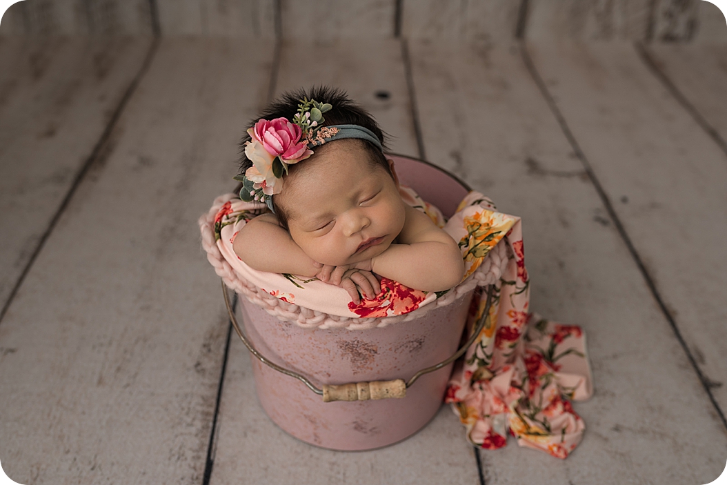 baby lays in bucket with floral wrap during Utah Newborn Session