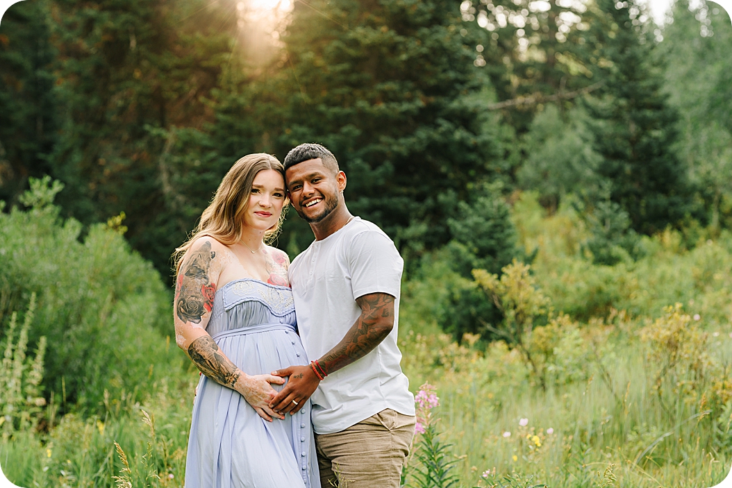 expecting parents hug in field during canyon maternity portraits