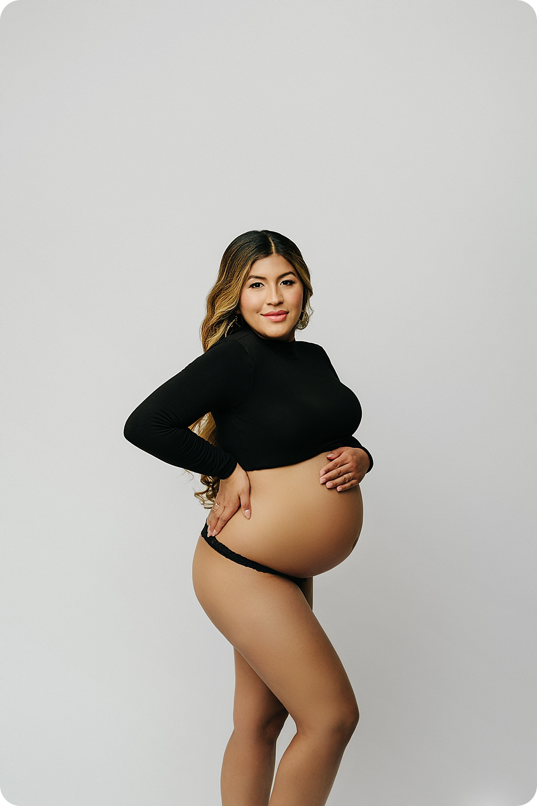 expecting mom holds belly during fashion inspired maternity session