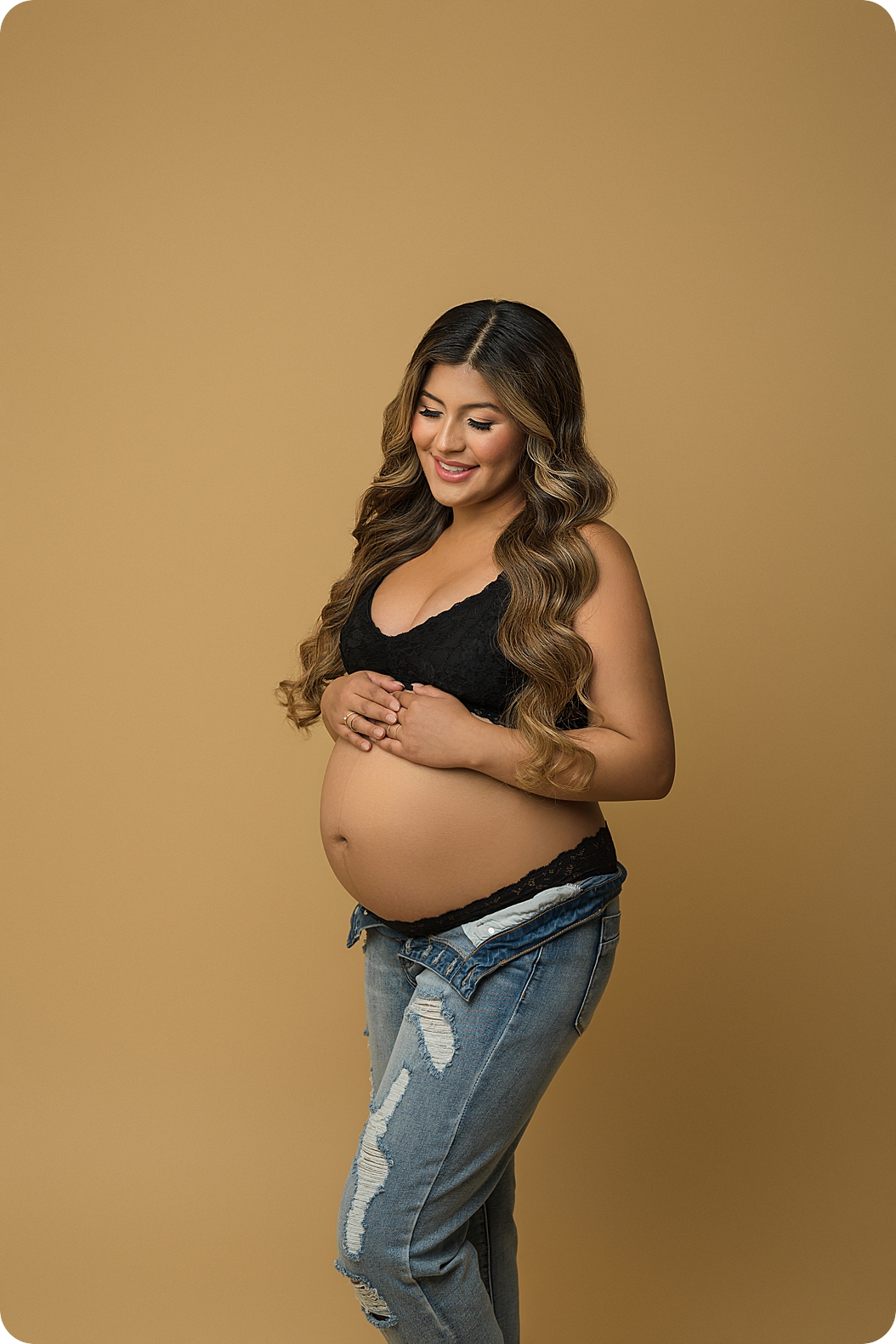 woman stands in Utah studio holding baby belly during fashion inspired maternity session