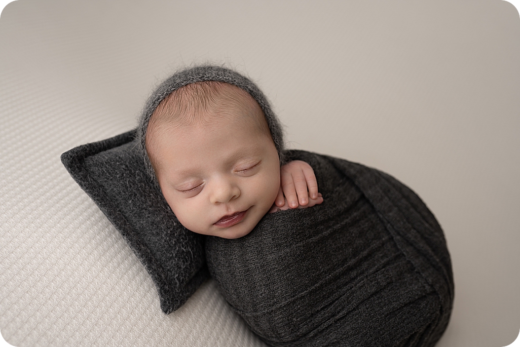 baby sleeps with hand curled under chin during neutral toned newborn session