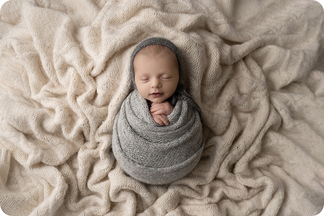 baby sleeps in grey wrap during neutral toned newborn session