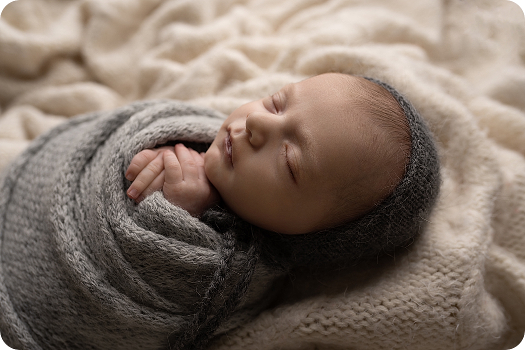 baby in grey wrap sleeps during neutral toned newborn session
