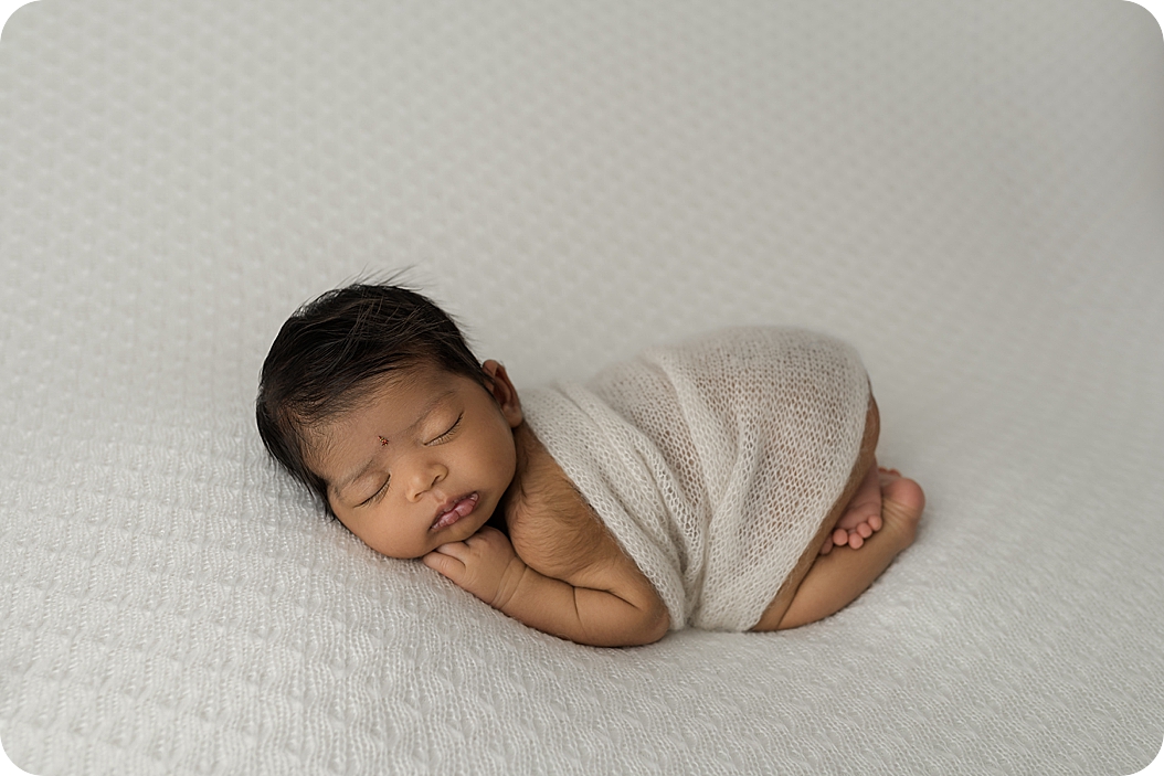 baby in white wrap sleeps during UT newborn portraits 