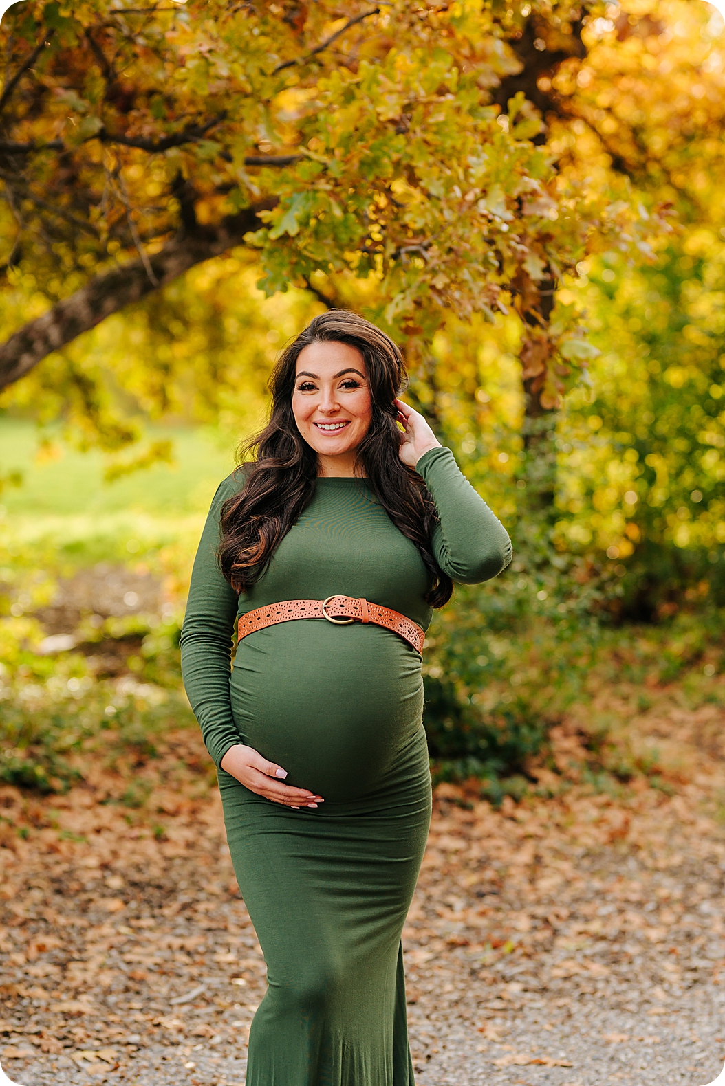 woman pushes hair back during fall maternity portraits outside 