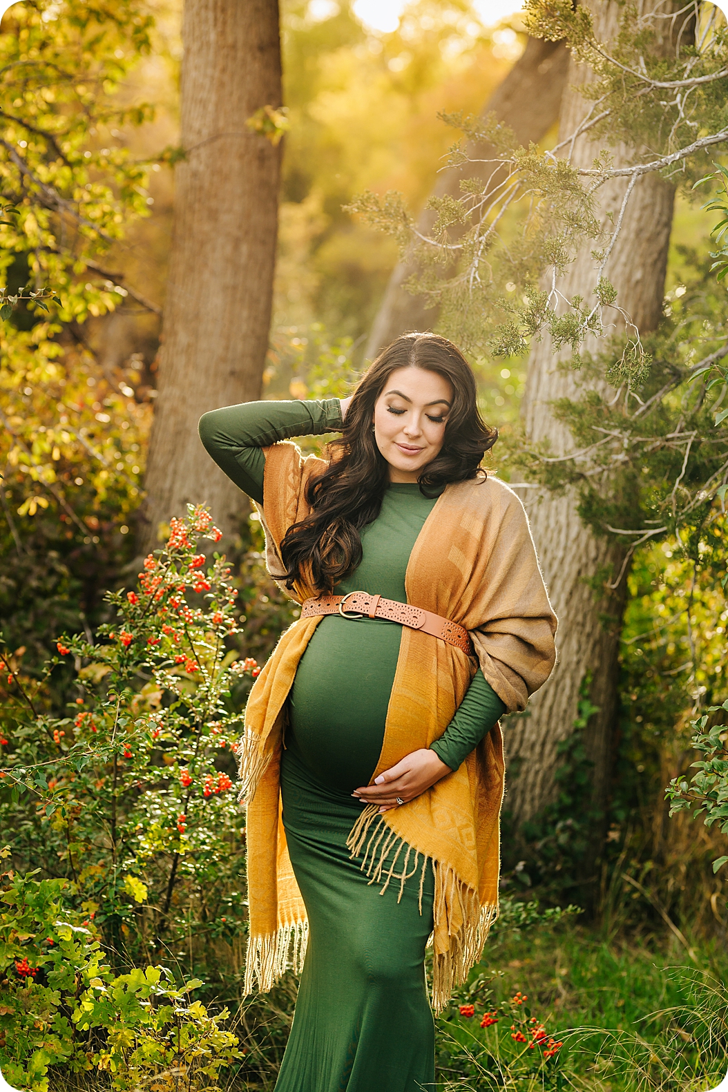 mom holds belly during fall maternity portraits