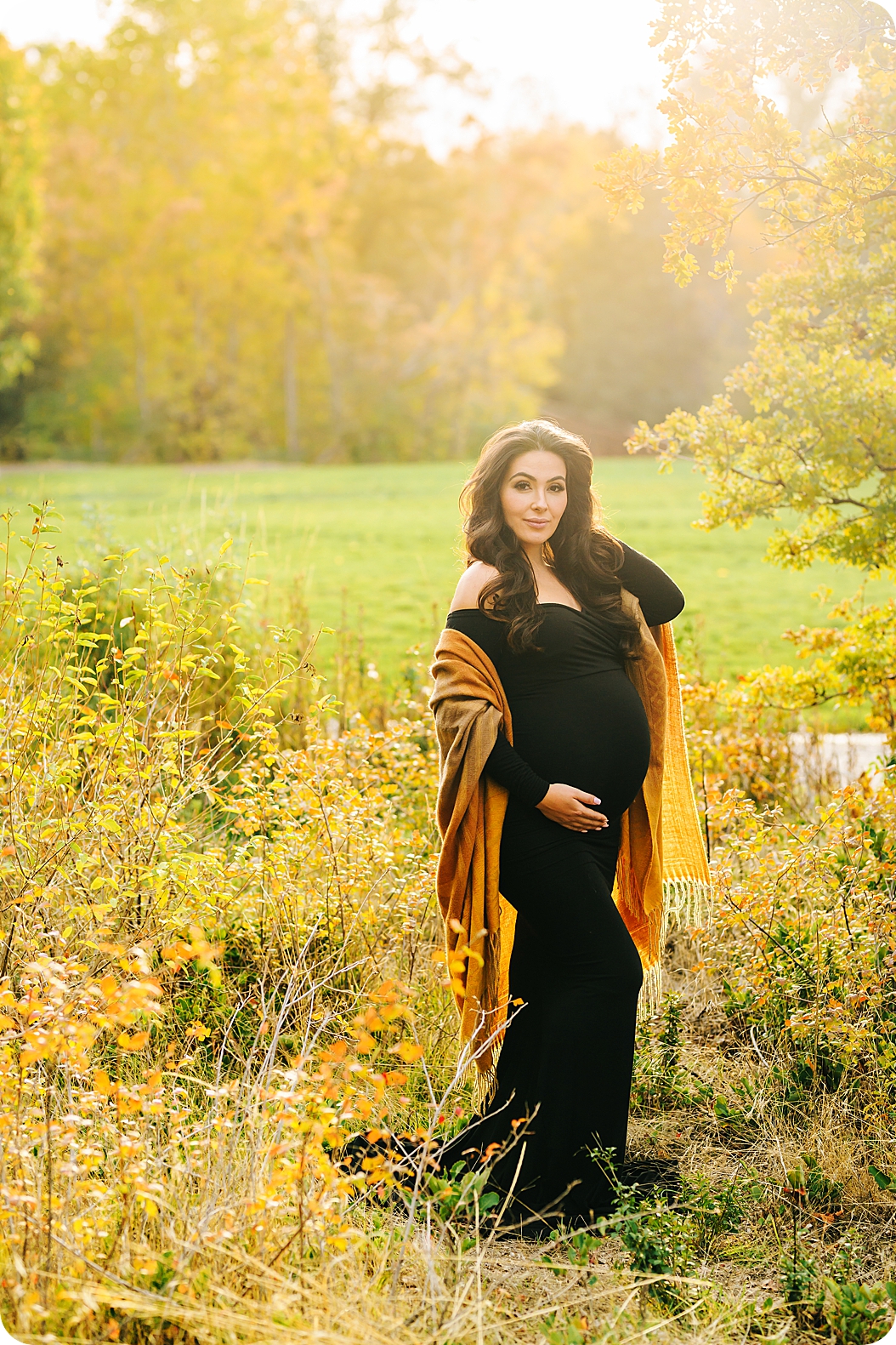 mom holds hair back during fall maternity portraits