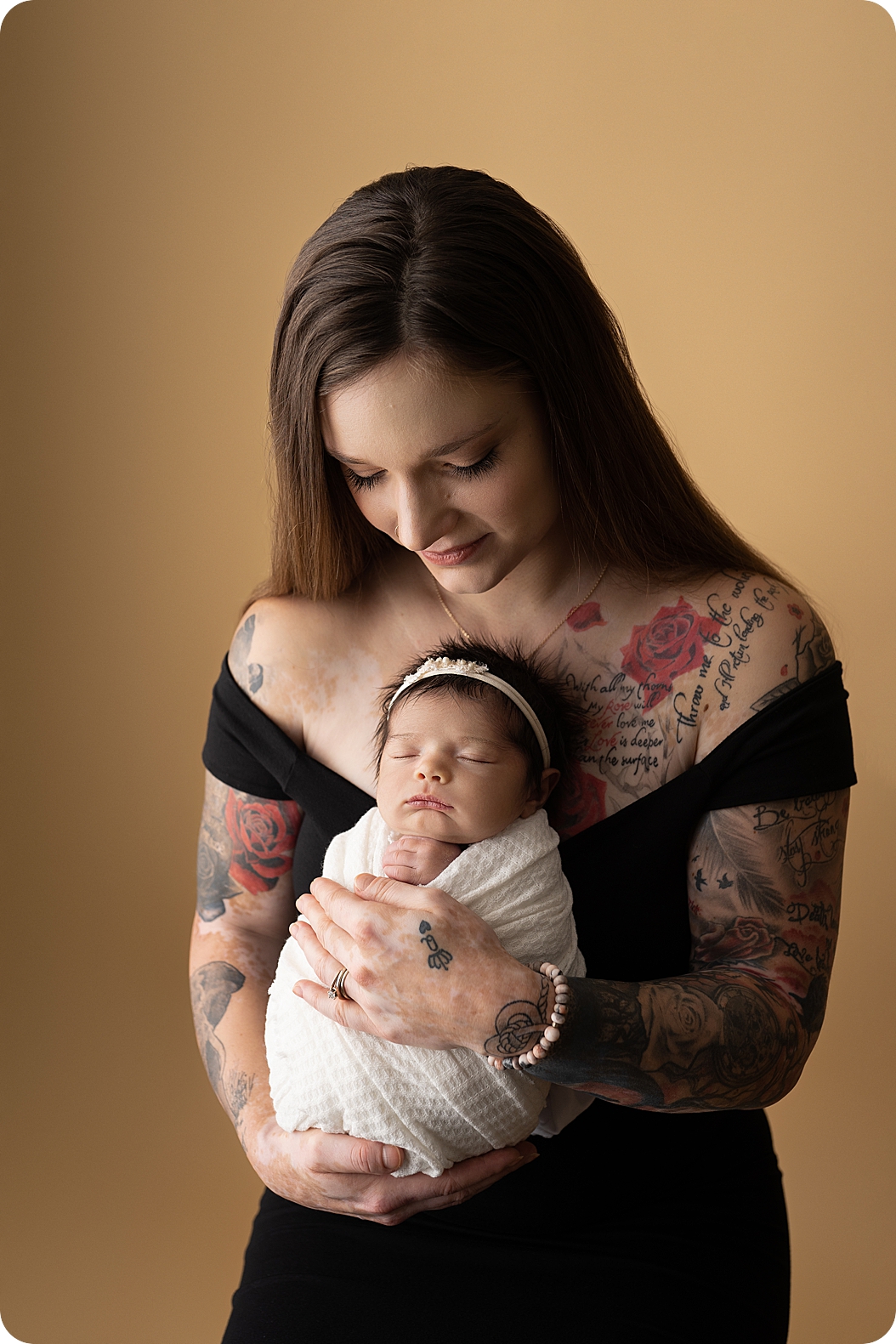 mom in black gown holds daughter during Utah newborn portraits