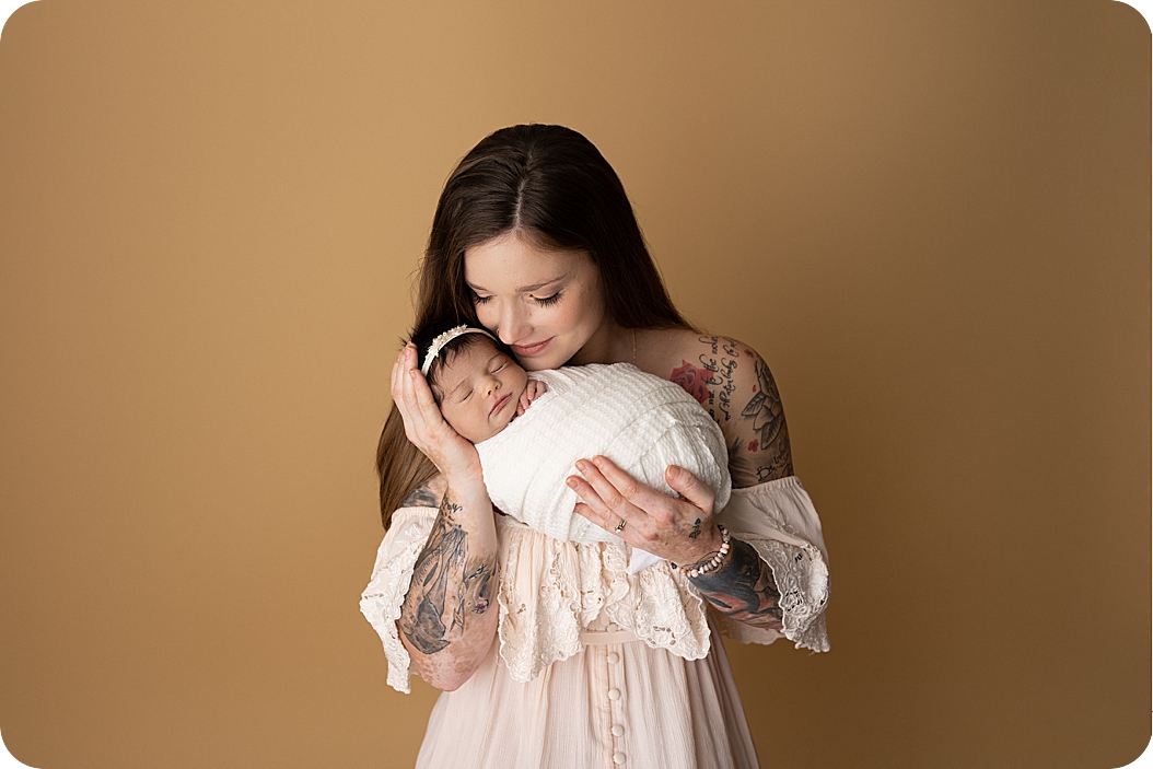 mom looks down at baby girl during Utah newborn portraits
