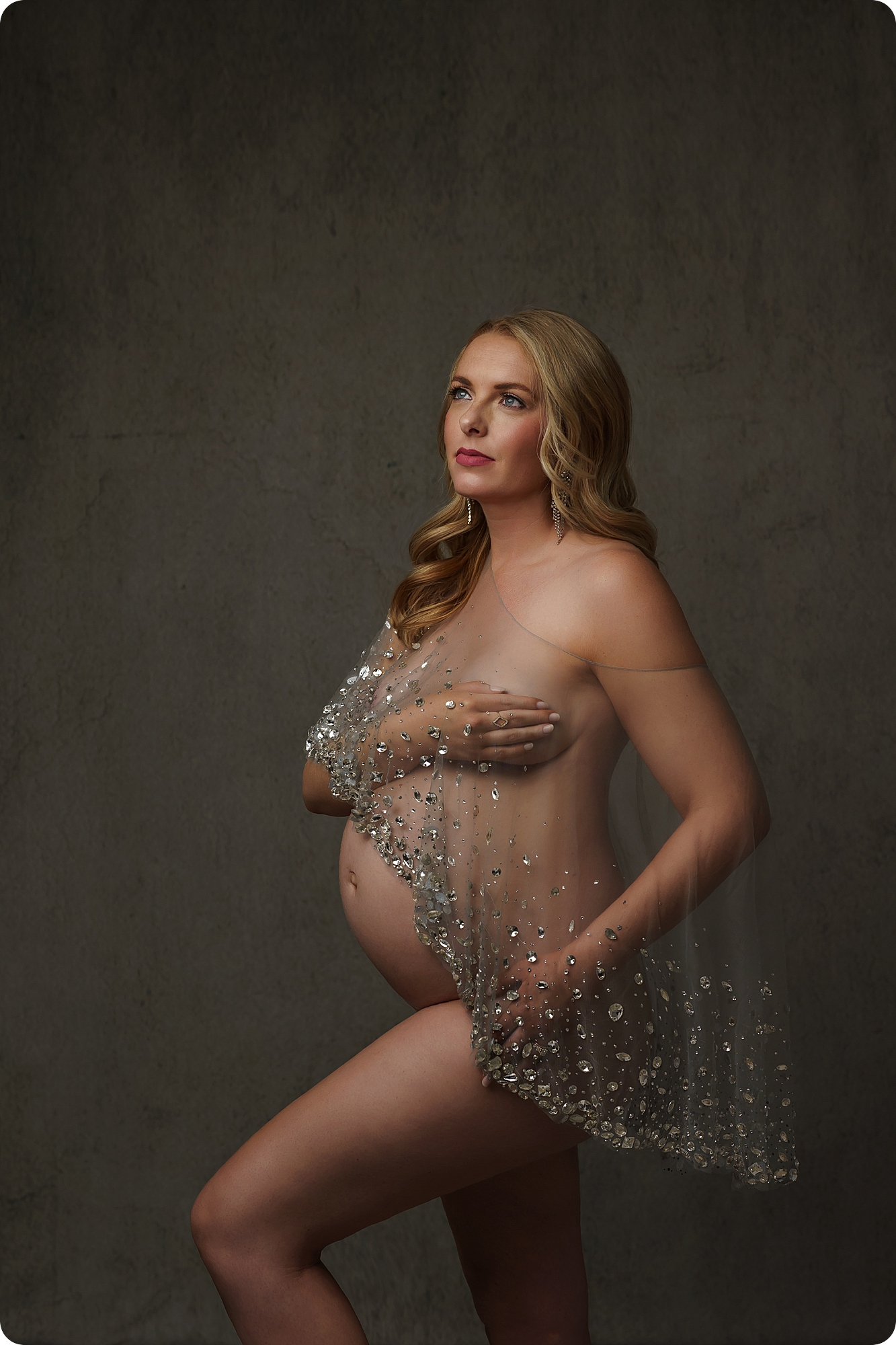mom holds belly during studio maternity portraits